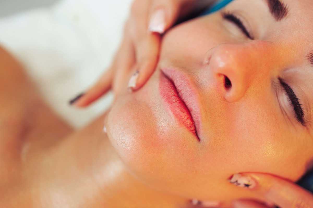 Twarz zrelaksowanej kobiety podczas masażu twarzy